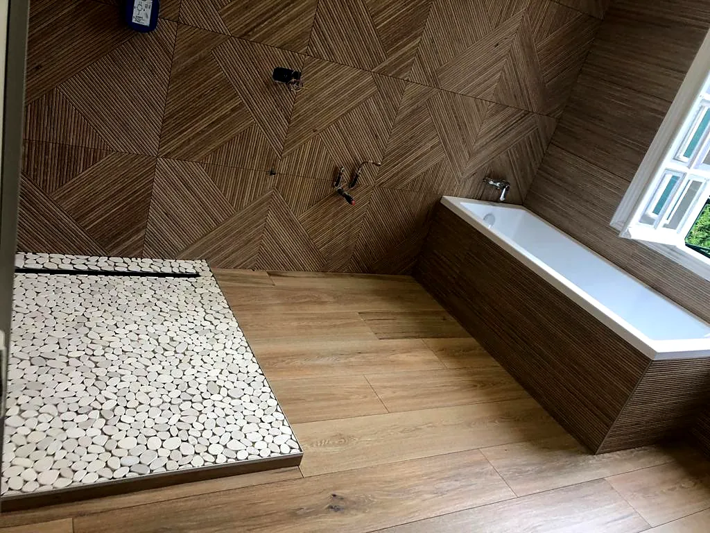 Receveur en galets, baignoire habillée et carrelage à chevrons
