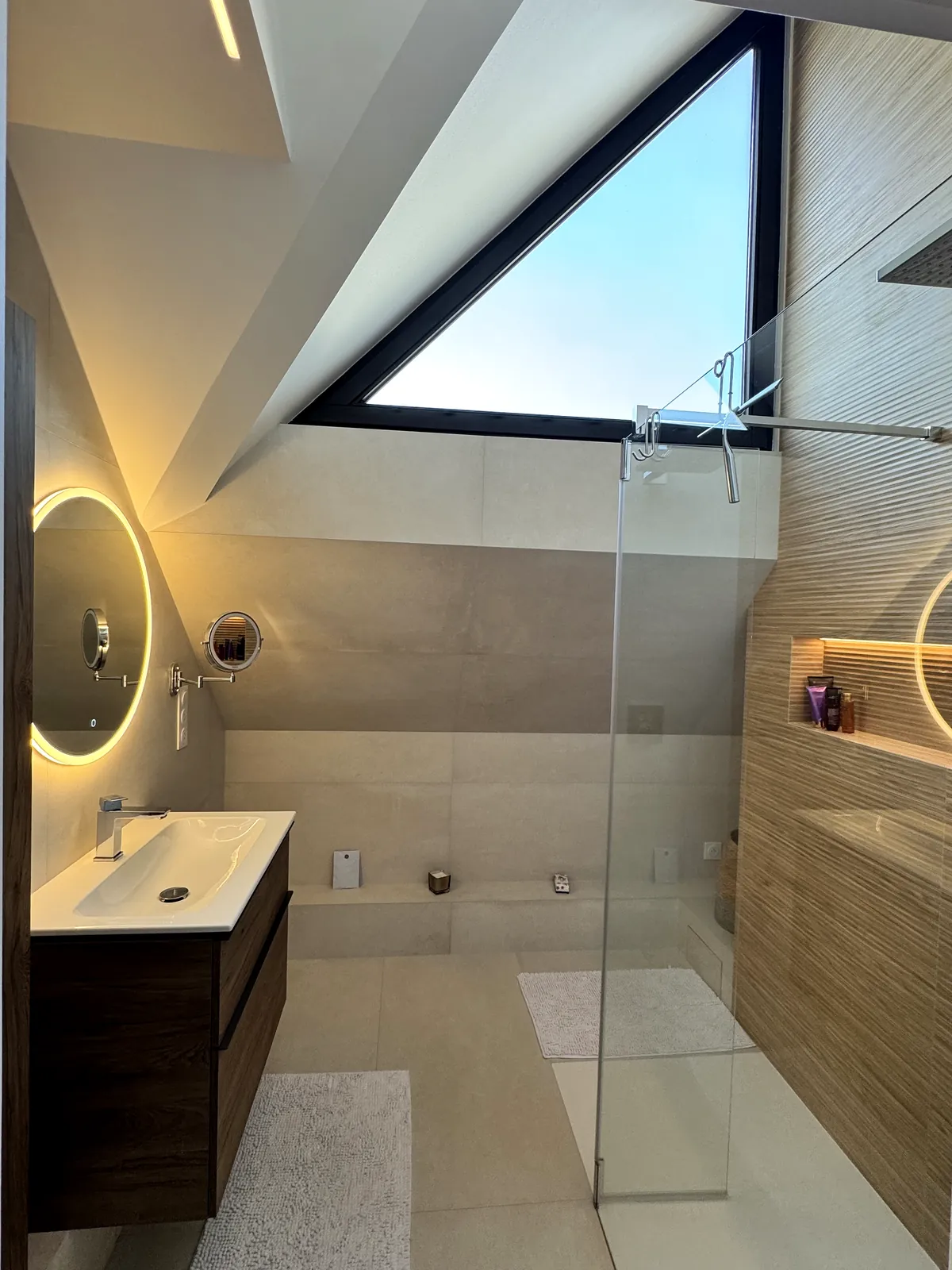 Salle d'eau terminée sous la fenêtre triangulaire : meuble vasque, miroir rétroéclairé, douche à l'italienne