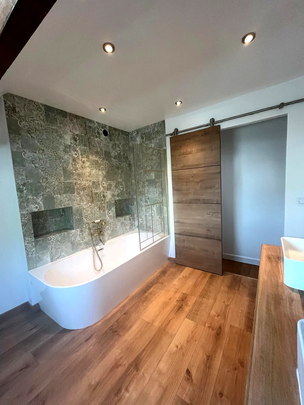 Suite parentale sous combles : baignoire îlot et mur effet pierre