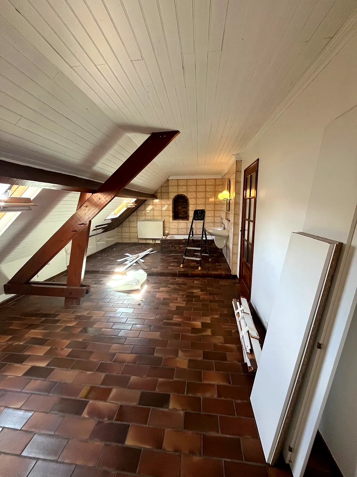Combles avant travaux : charpente apparente et ancien carrelage