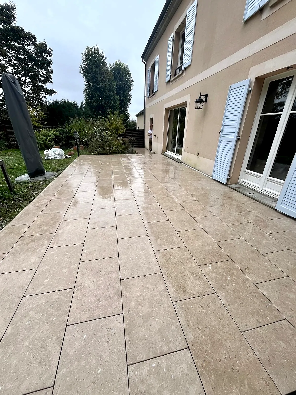 Terrasse en dallage effet pierre devant les baies de la maison