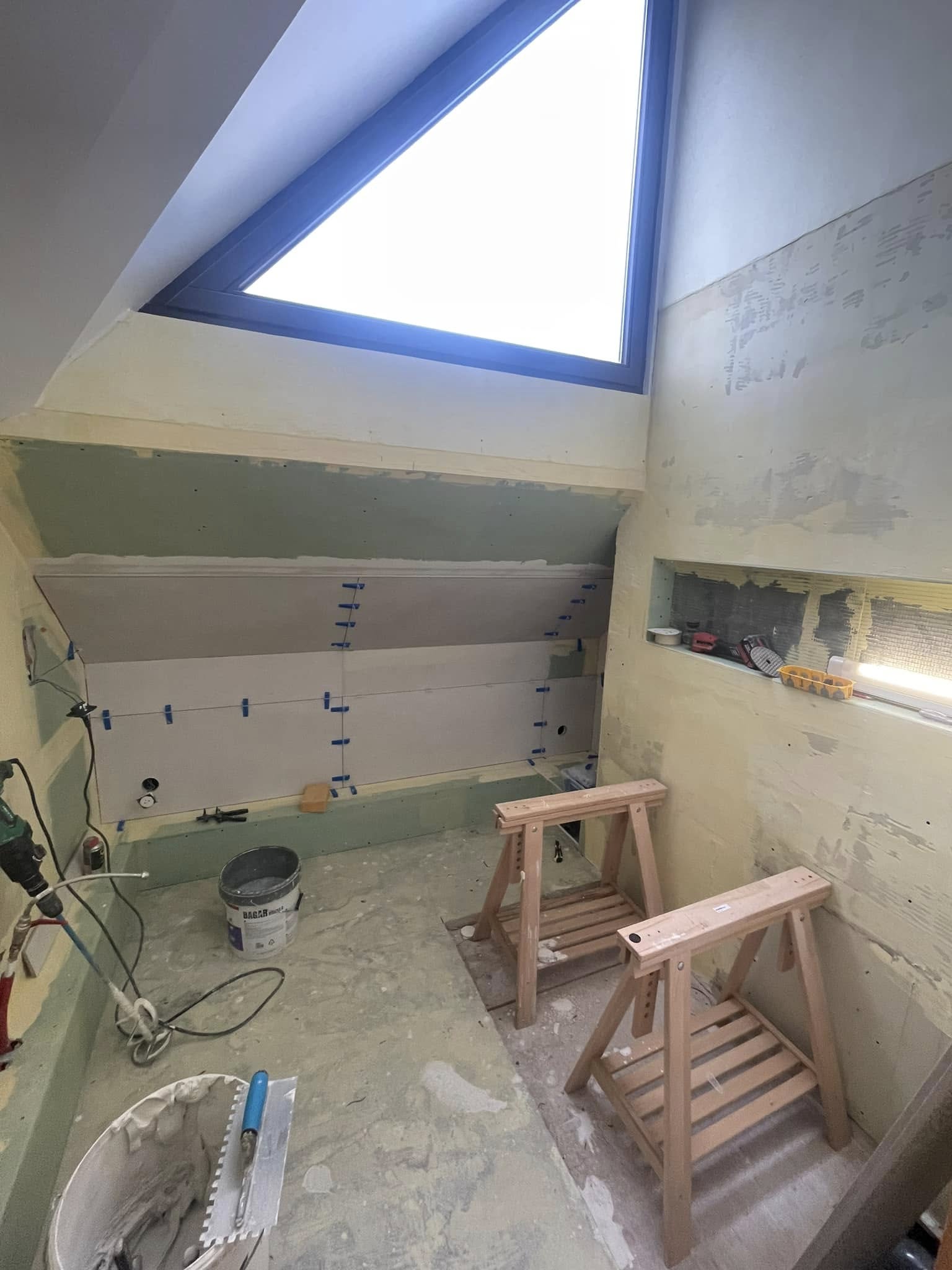 Salle de bains avant travaux — pose du carrelage en cours, tréteaux